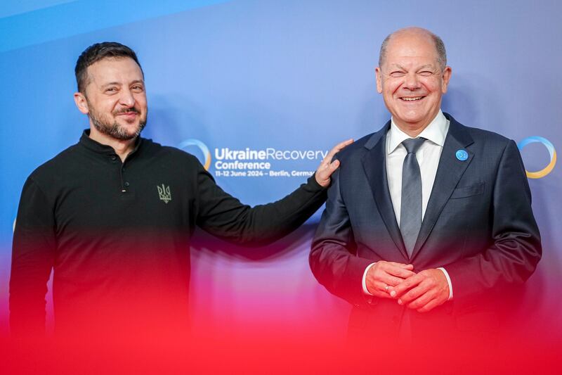 Ukrainian President Volodymyr Zelensky, left, puts his hand on German Chancellor Olaf Scholz’ shoulder as he is welcomed at the start of a conference (Kay Nietfeld/AP)