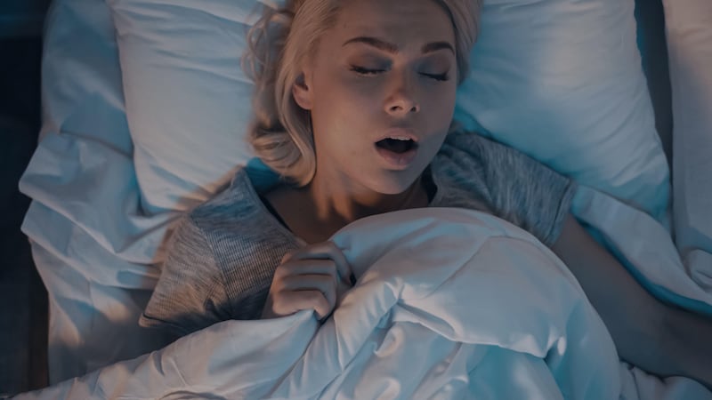 Young blonde woman snoring in bed