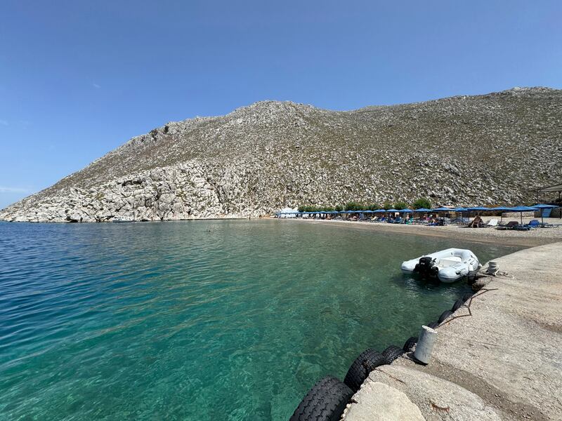 People sit on the beach of Agios Nikolaos from where doctor and television presenter Michael Mosley, is believed to have set out (Antonis Mystiloglou/AP)