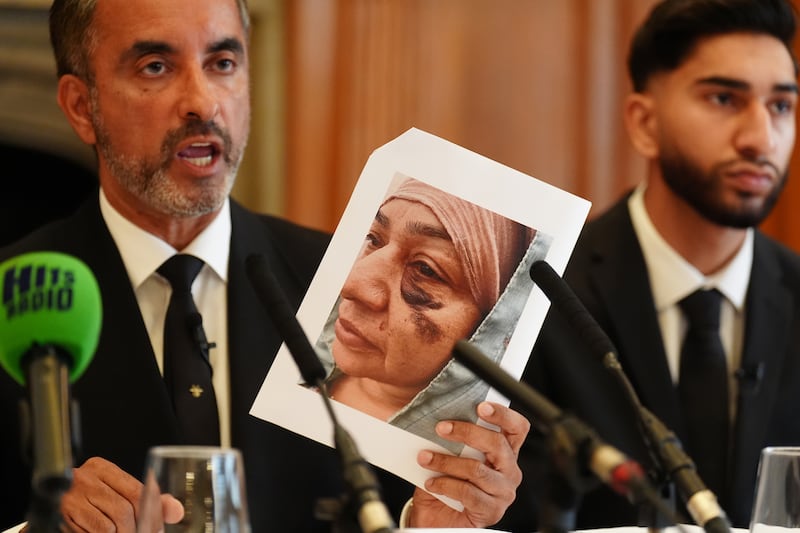 Solictor Aamer Anwar, holds up a picture of Shameem Akhtar as her son Fahir Amaaz, 19, looks on during the press conference