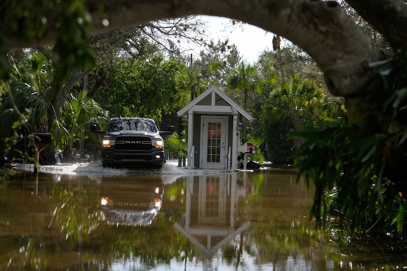 A car drives past a guard gate on a flooded street in Siesta Key, Florida (Rebecca Blackwell/AP)