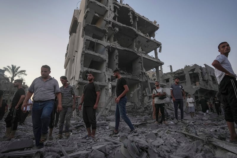 Palestinians stand in rubble after an Israeli air strike in Deir al Balah in the Gaza Strip (Abdel Kareem Hana/AP)