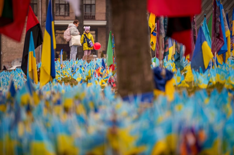 A child holds a balloon while looking at a memorial for soldiers killed in the war (Vadim Ghirda/AP)