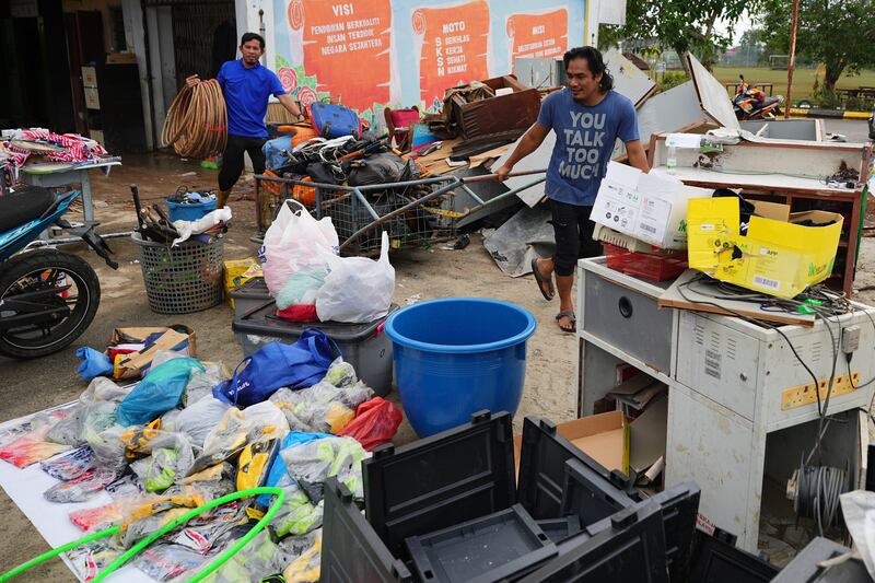 Men remove items from a school affected by a flood in Tumpat, on the outskirts of Kota Bahru, Malaysia (Vincent Thian/AP)