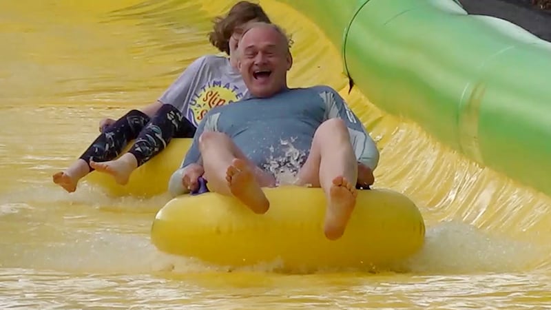 Sir Ed Davey speeds down the Ultimate Slip n Slide attraction near Frome, Somerset