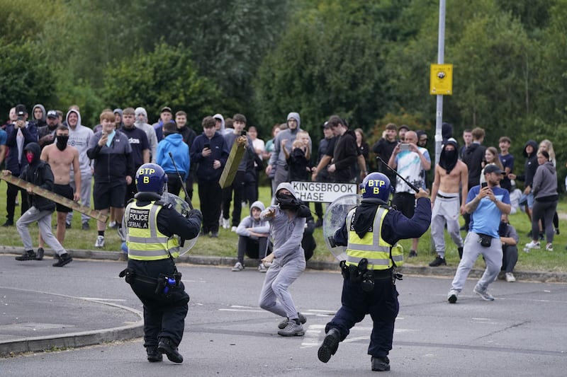 A youth throws a fence post towards police during an anti-immigration demonstration near the Holiday Inn Express in Rotherham, South Yorkshire, on Sunday