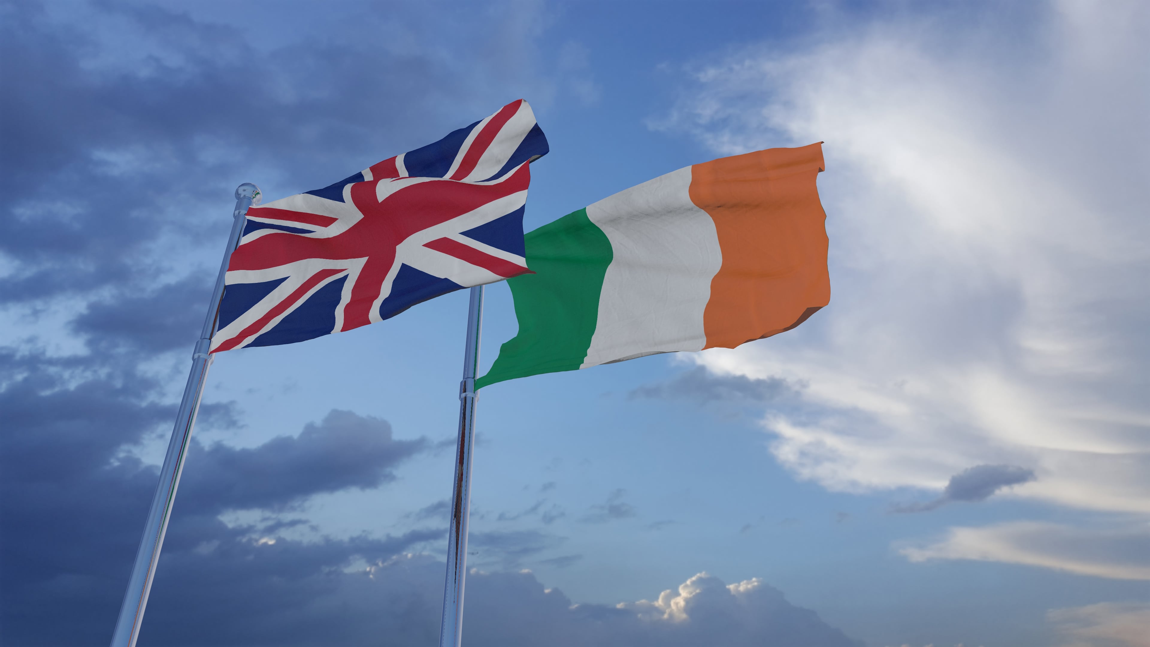The flags of Ireland the UK on lamposts against a sky