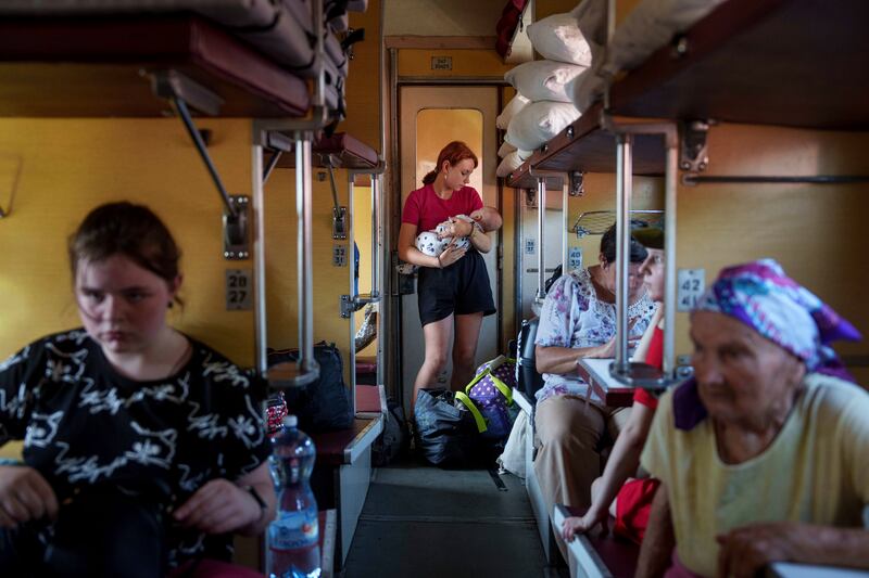 A girl calms her sister on an evacuation train in Pokrovsk, Donetsk region, Ukraine (Evgeniy Maloletka/AP)