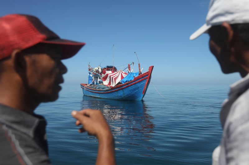 Acehnese men inspect a boat carrying Rohingya refugees anchored in the waters off the coast of Aceh, Indonesia’s northernmost province (Binsar Bakkara/AP)