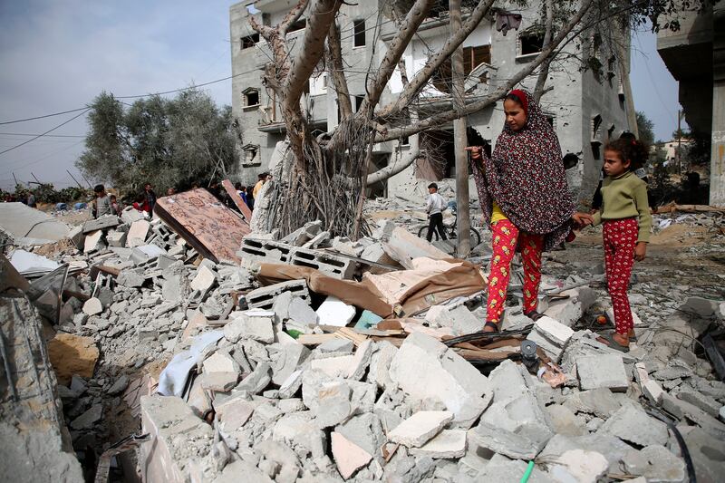 Palestinians inspect the ruins of a residential building in Rafah (Hatem Ali/AP)
