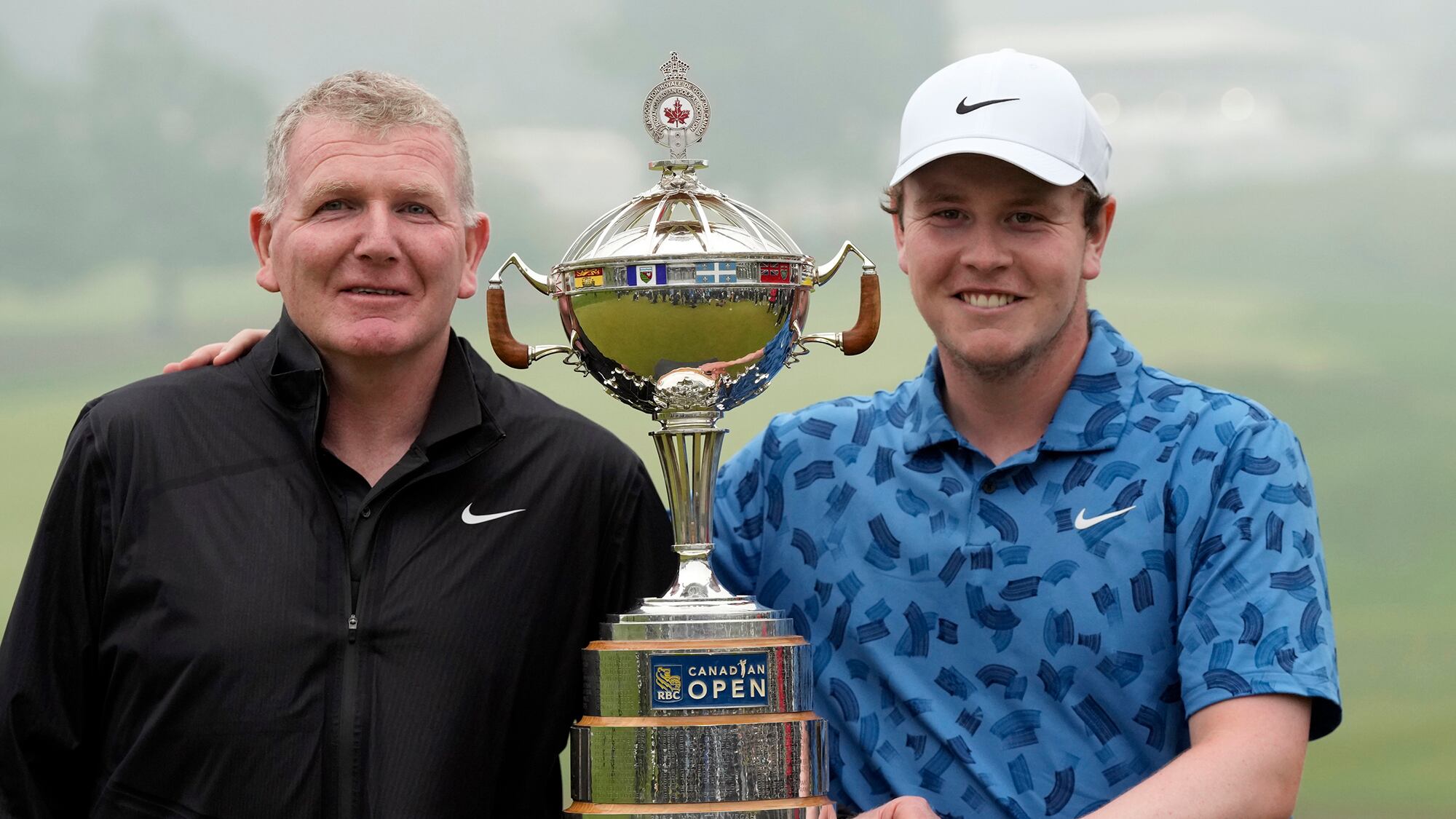 Scotland’s Robert MacIntyre (right) and his father and caddie Dougie pose for photos with the RBC Canadian Open trophy (Frank Gunn/The Canadian Press via AP)