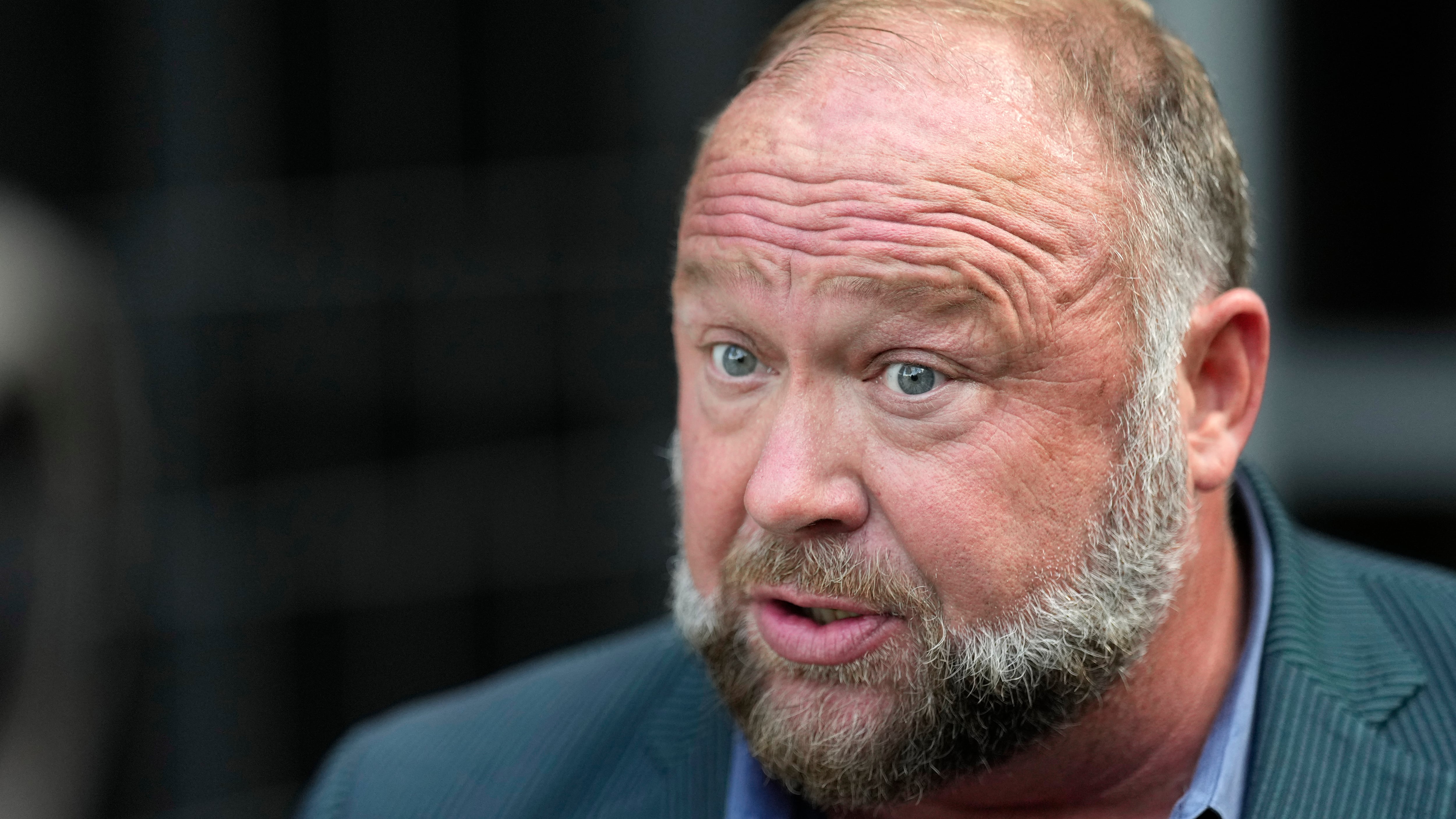 Alex Jones speaks to the media after arriving at court in Houston, Texas, for a hearing in front of a bankruptcy judge on Friday (David J Phillip/AP)