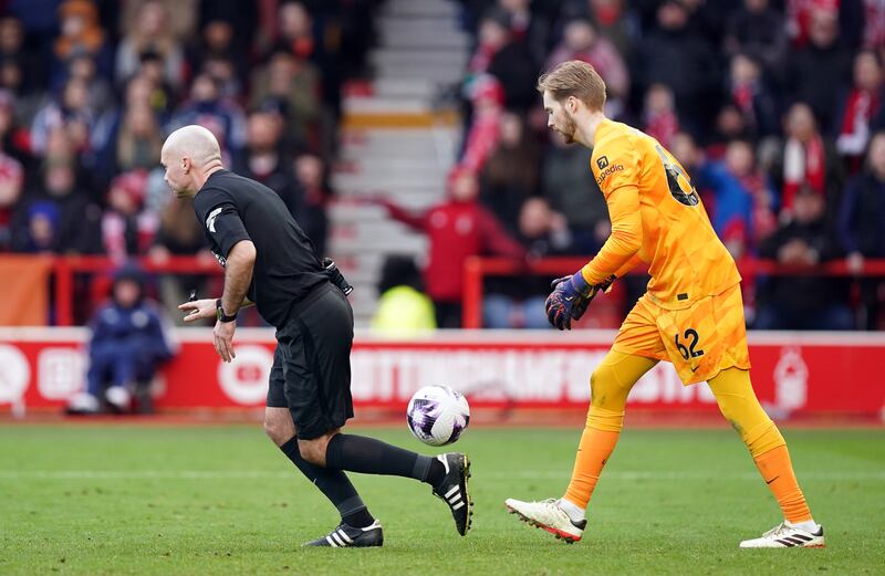 Referee Paul Tierney allows play to restart with Liverpool goalkeeper Caoimhin Kelleher .