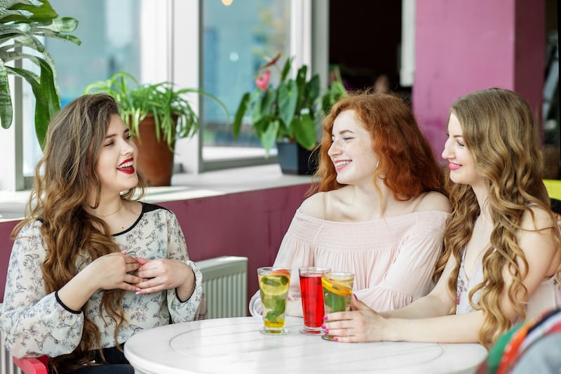 Three happy young women chatting in a cafe