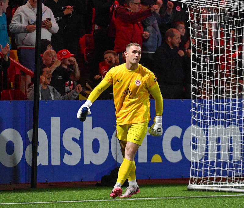 A football player in a yellow jersey walking away from goal