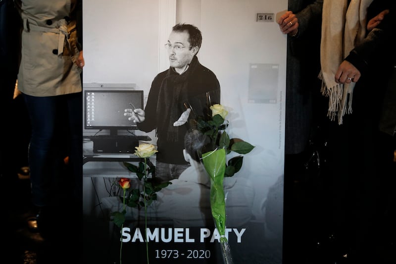 People hold a photo of the history teacher Samuel Paty (Lewis Joly/AP)