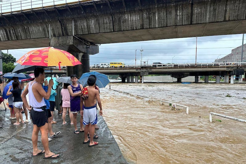 People watch the Marikina River as it floods from monsoon rains in Manila (Joeal Capulitan/AP)