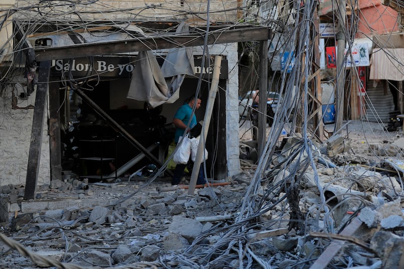 A man carries his belongings in the debris of destroyed buildings in Tyre (Mohammed Zaatari/AP)