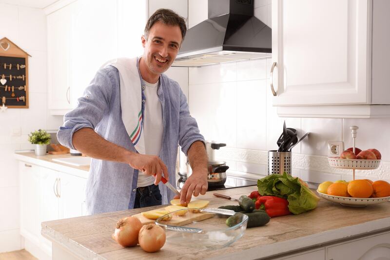 A man chopping veg and potatoes in the kitchen