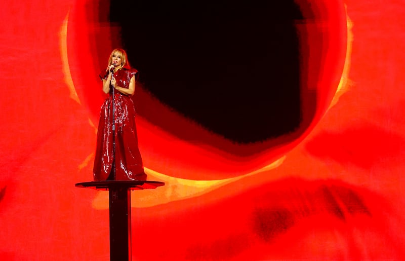 Kylie Minogue on a podium in a red leather-style ensemble