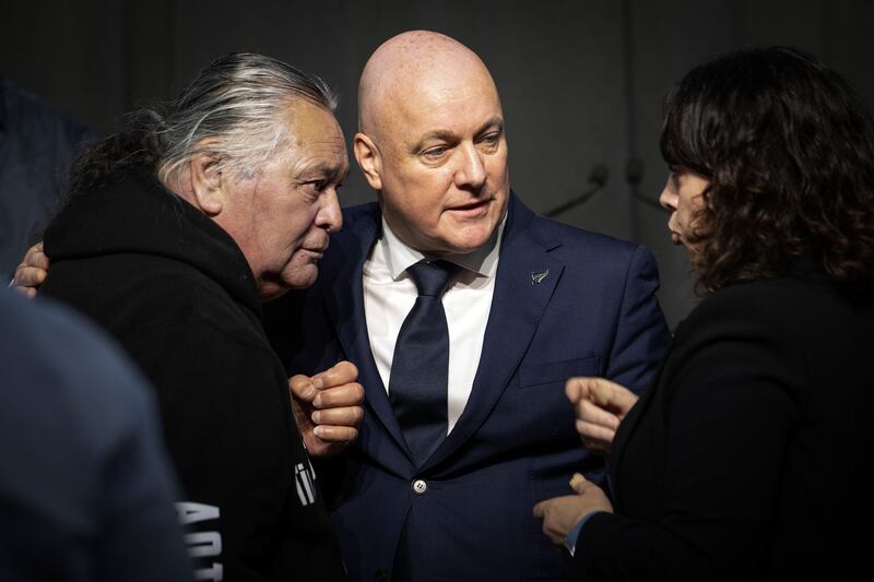 New Zealand’s Prime Minister Christopher Luxon talks to survivor Whiti Ronaki, left, and Laura Cherrington (Monique Ford/Stuff via AP)