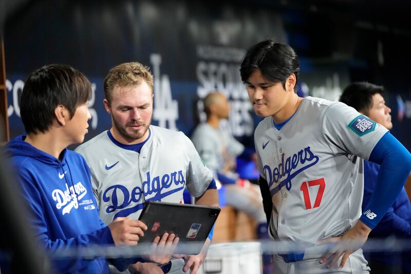 Los Angeles Dodgers’ Gavin Lux, centre, and Shohei Ohtani, right, talk with interpreter Ippei Mizuhara during the first inning of an opening day baseball game against the San Diego Padres in Seoul (Lee Jin-man/AP)