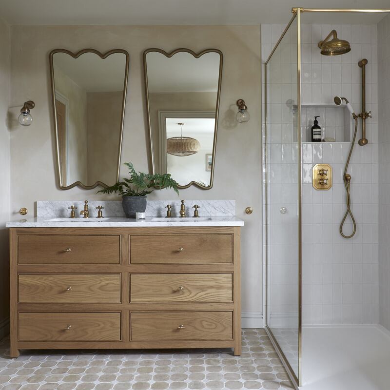 Statement mirrors paired with an oak vanity unit creates a striking focal point in this timeless en-suite bathroom by Souq.Studio