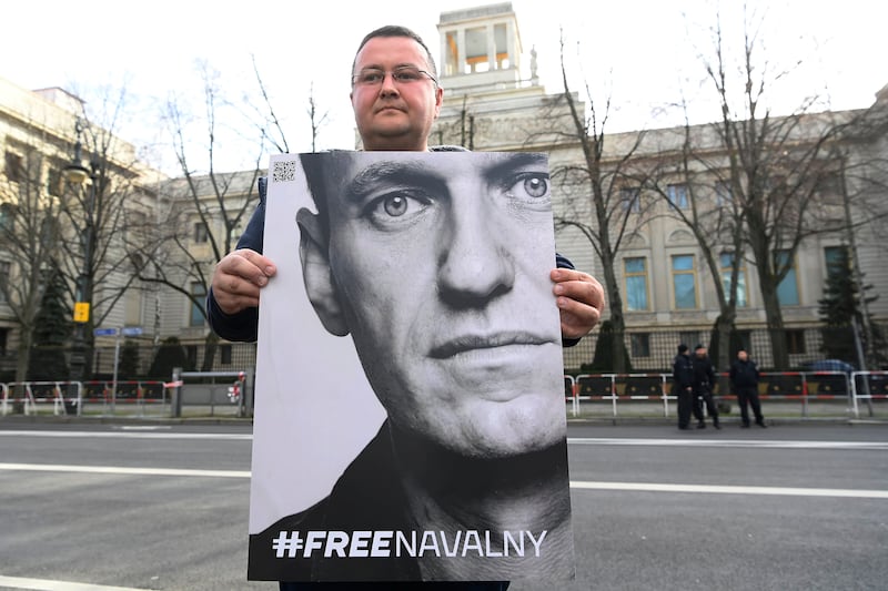 A man holds a poster with the portrait of Alexei Navalny in front of the Russian embassy in Berlin, Germany, after hearing news of his death (Paul Zinken/dpa via AP)