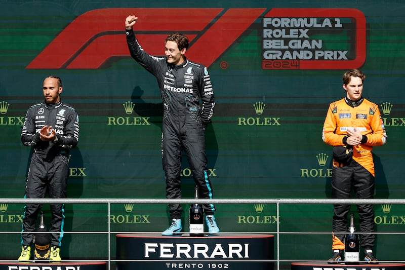 Russell celebrates on the podium alongside Hamilton (left) and Oscar Piastri (right) (Geert Vanden Wijngaert/AP)