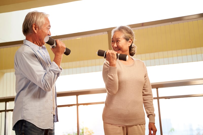 Happy Asian elderly couple lifting weights