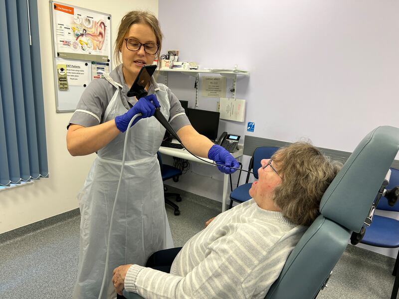 EMBARGOED UNTIL 0001 NOVEMBER 2 Nina Glazzard, advanced clinical practitioner for ears, nose and throat, using the endoscope-I adapter on Janet Hennessy, 76, from Bradeley, Stoke-on-Trent, as part of a trial at North Midlands University Hospitals NHS Trust. The adapter includes a 32mm lens that attaches to an iPhone, turning it into a portable endoscope to help the NHS rule out throat cancer in patients faster.