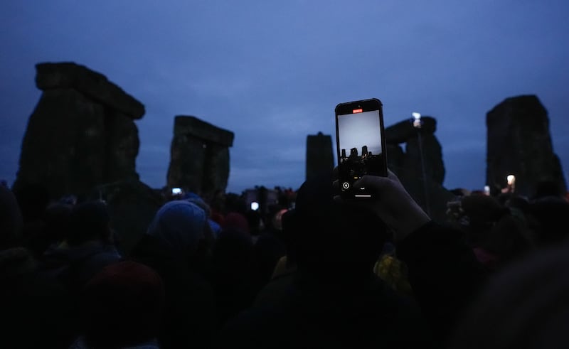 A person films on their phone as people take part in the winter solstice celebrations