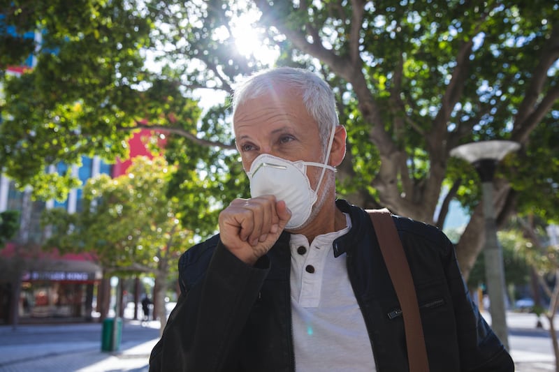 Senior man wearing Covid 19 mask while walking down a street