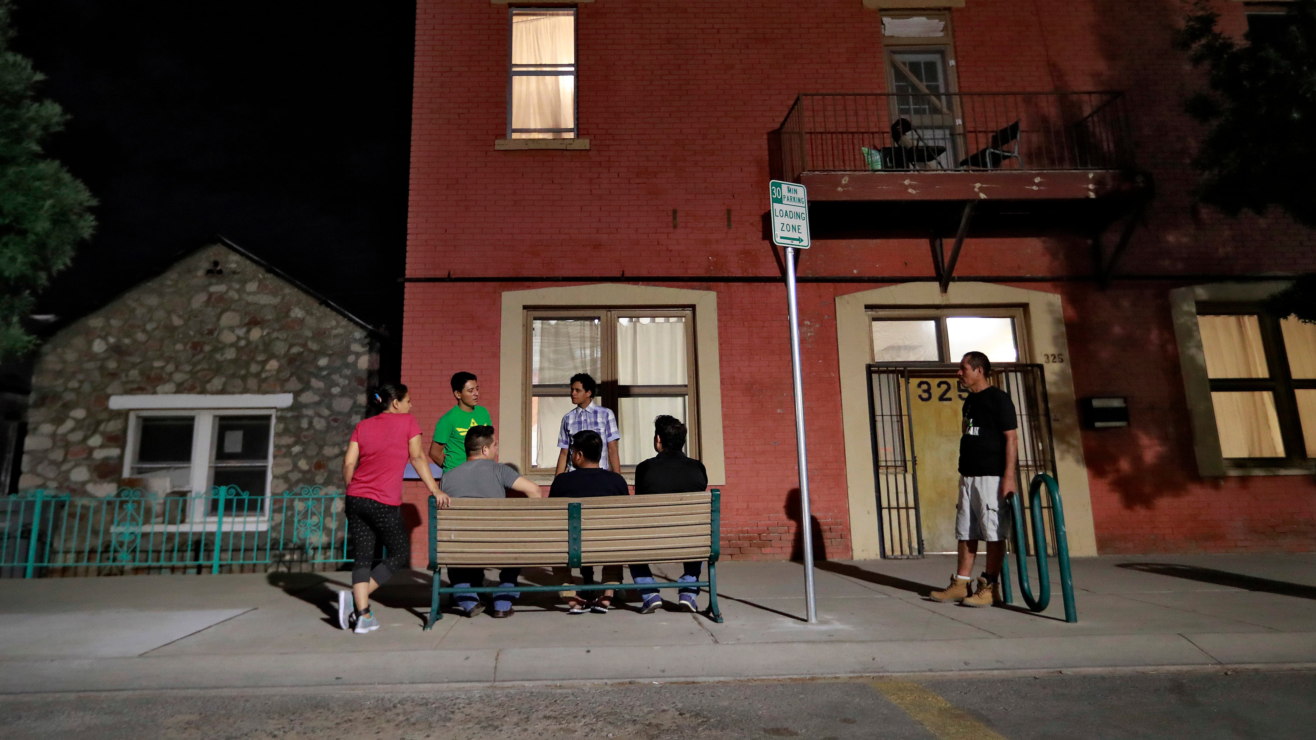 Migrant parents socialise outside the Annunciation House in El Paso (Matt York/AP)
