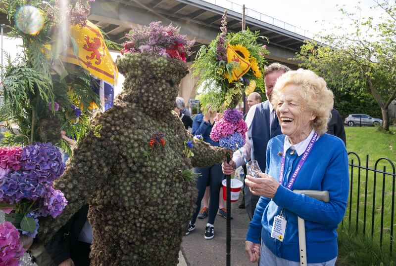 The Burryman gets a dram from Kathleen Hamblin, right, during the parade