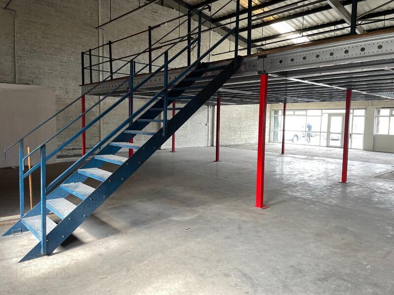 Interior of empty business unit with blue metal stairs.