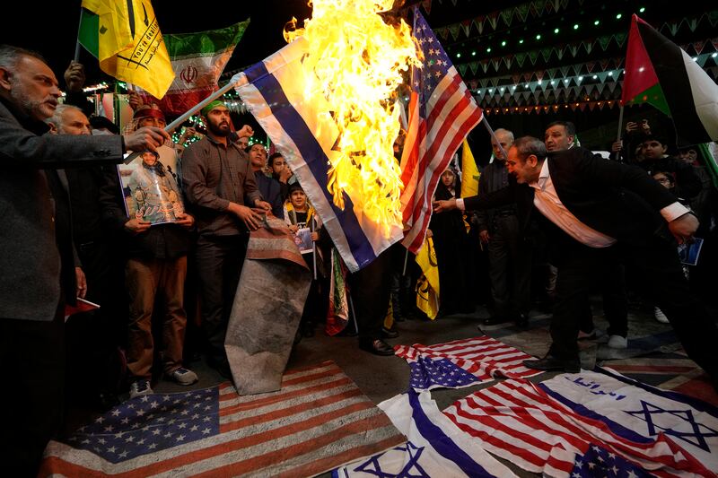 Iranian protesters burn representations of the US and Israeli flags. It comes as IRNA said Iran holds the United States, Israel’s closest ally, responsible for the strike (AP Photo/Vahid Salemi)