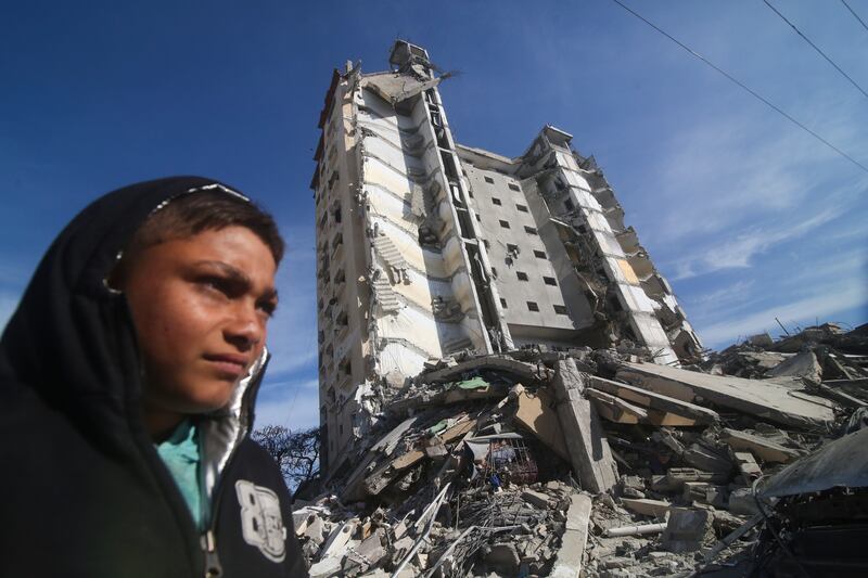 Palestinians walk by a residential building destroyed in an Israeli strike in Rafah, Gaza Strip (AP)