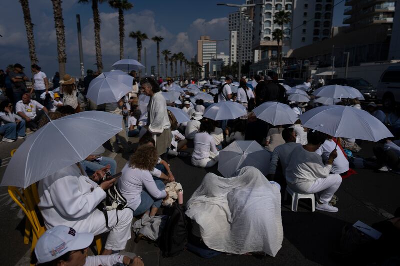 Activists sit on a road with white umbrellas during a protest calling for the release of hostages held in the Gaza Strip (Oded Balilty/AP)