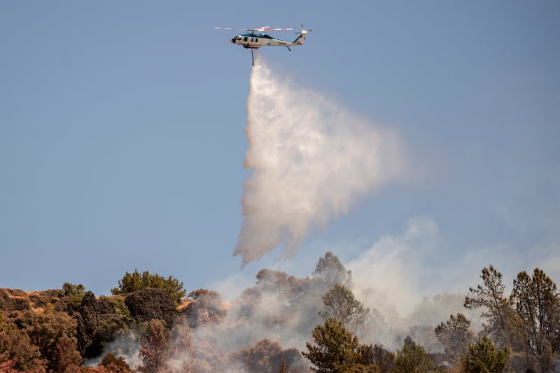 A Pacific Gas and Electric Company firefighting helicopter releases water over the Thompson Fire in Oroville, California (Stephen Lam/San Francisco Chronicle/AP)