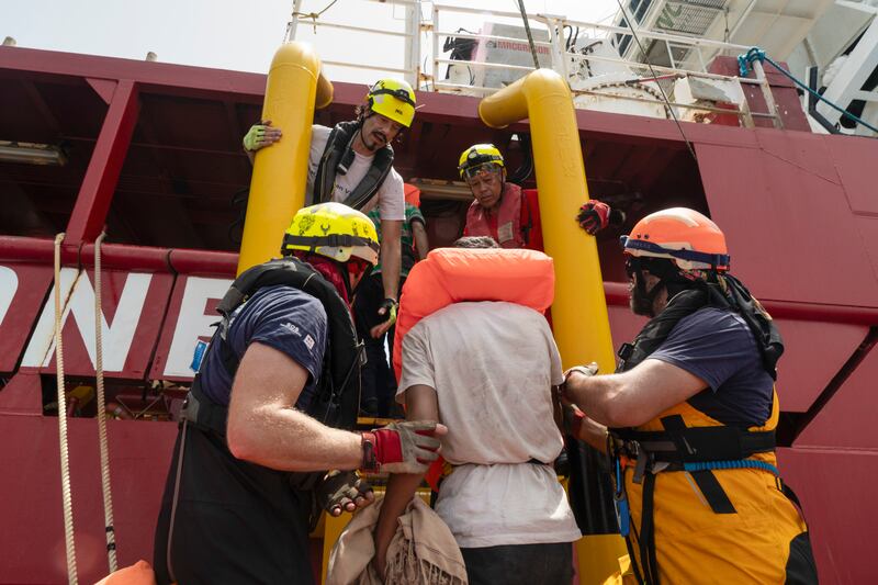 Rescue personnel help transfer the passengers from a wooden migrant boat (Charles Thiefaine/SOS Mediterranee via AP)