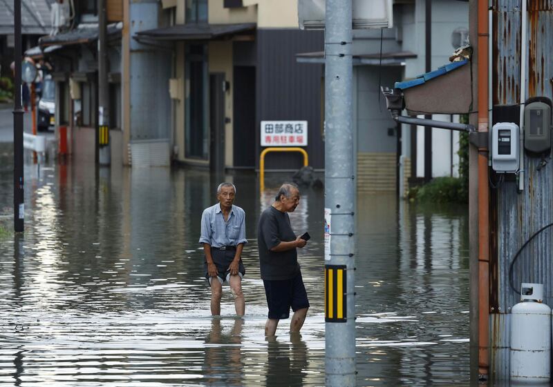 People wade through a flooded street after heavy rain caused by the storm in Ogaki, central Japan (Natsumi Yasumoto/Kyodo News/AP)