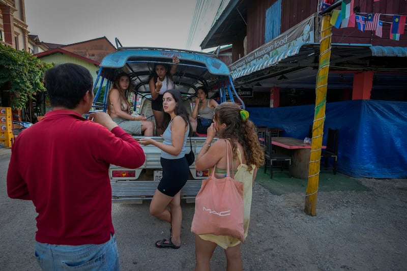 Tourists talk to a bar owner in Vang Vieng, Laos (Anupam Nath/AP)