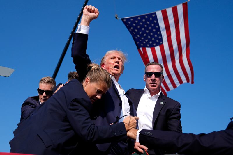 Republican presidential candidate former president Donald Trump is surrounded by US Secret Service agents after an assassination attempt at a campaign rally (Evan Vucci/AP)