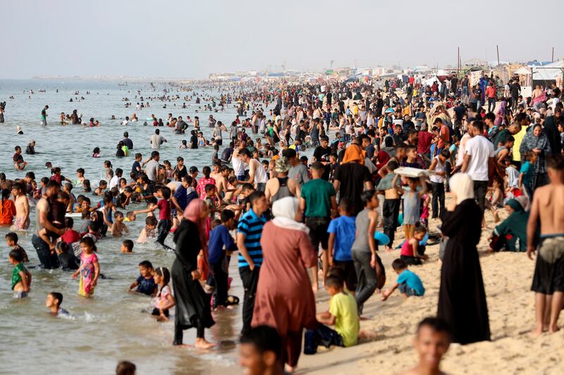 Palestinian family members displaced by the ongoing war with Israel on the beach during a heatwave in southern Gaza (Saher Alghorra/AP)
