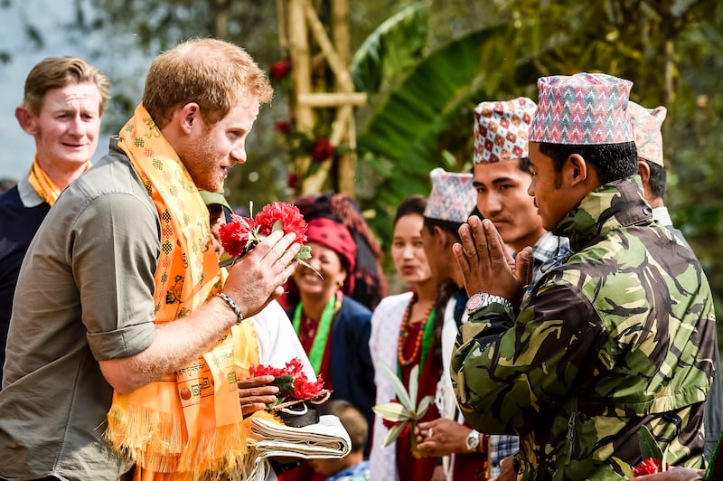 Harry gives a namaste greeting as he arrives at an earthquake-stricken village in Nepal in 2016