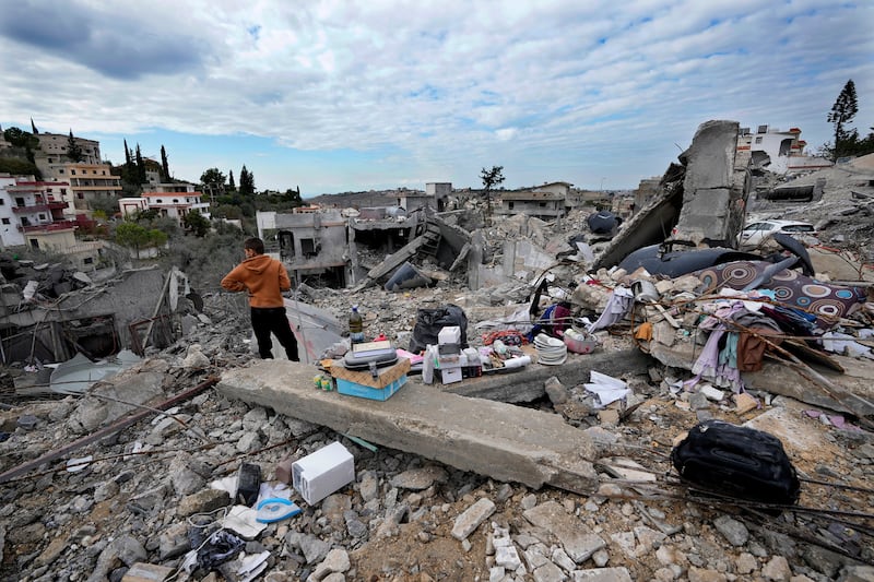 A person stands next to remains of his family home after he returned to Chehabiyeh village, southern Lebanon