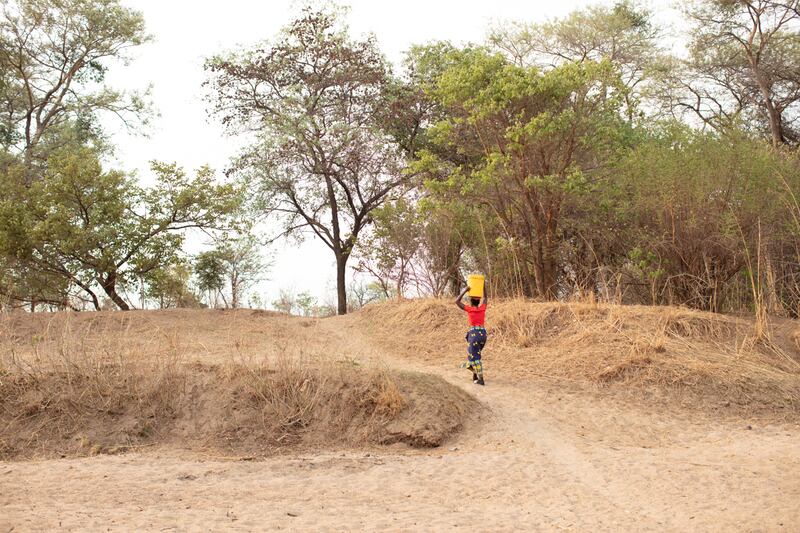 A women collecting and carrying water from a dried up riverbed, Mukobela community, Zambia. (WaterAid/Laura Pannack)