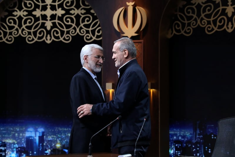 Iranian presidential candidate Saeed Jalili, left, and reformist candidate Masoud Pezeshkian greet one another at the conclusion of a TV debate (Morteza Fakhri Nezhad/AP)