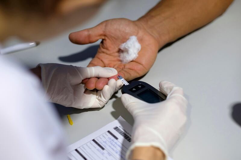 Medical worker using a blood glucose meter to test a patient for diabetes